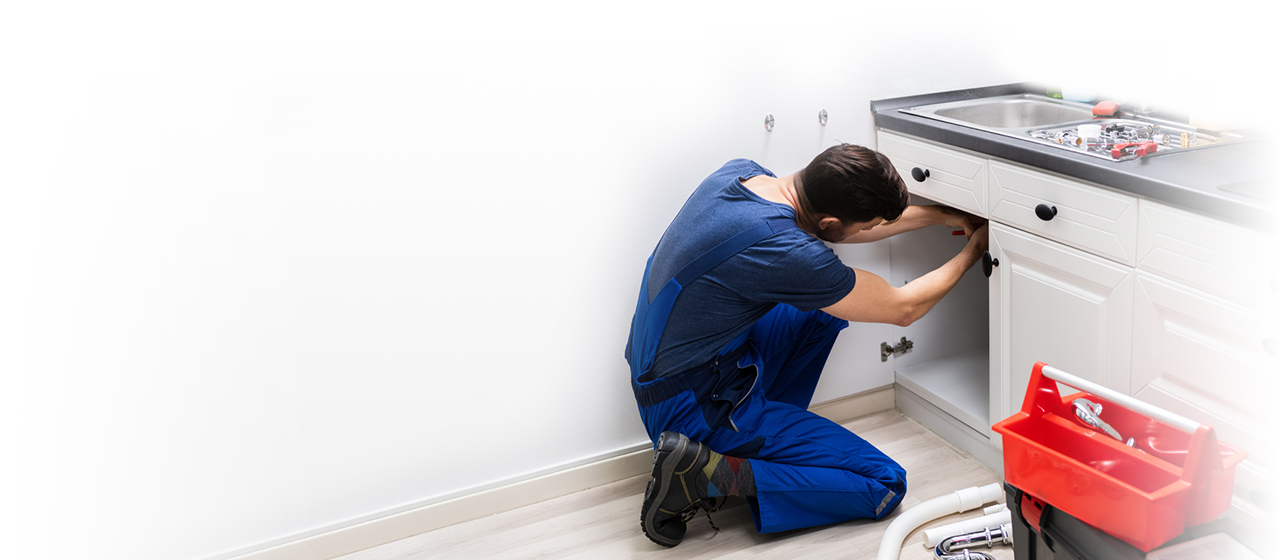 Man fixing pipe beneath sink